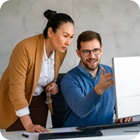 woman leaning over a mans shoulder looking at computer